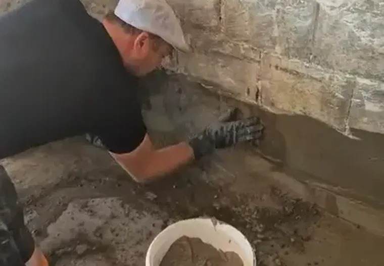 Vakman werkt de kimnaad tussen vloer en muur af met mortel