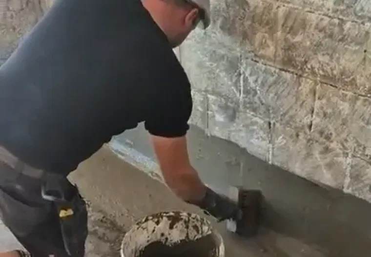 Vakman brengt de waterdichting aan op de voet van een binnenmuur