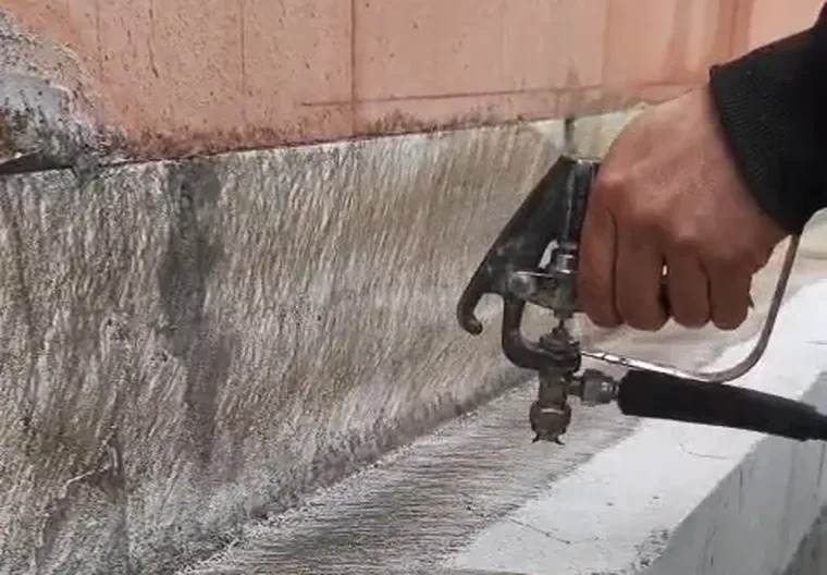 Primer wordt met een spuitpistool op de muurvoet aangebracht
